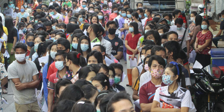In this Dec. 20 file photo, 2,000 Myanmar migrant workers wait in front of a dormitory near the Thai Union Market in Samut Sakhon, Thailand, as health officials conduct COVID-19 tests. / Arnun Chonmahatrakool / Bangkok Post