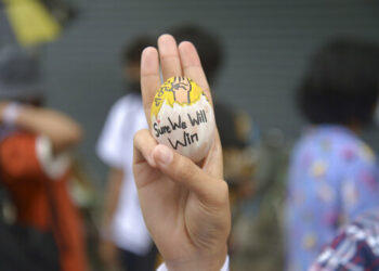 An anti-coup protester raises a decorated Easter egg along with the three-fingered symbol of resistance during a protest against the military coup on April 4, 2021 in Yangon. / AP