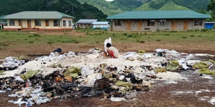 A local searches for rice among the wreckage of rice sacks and medicines burned by the Myanmar military on June 8. / PKPF