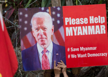 An anti-regime protester holds a placard featuring US President Joe Biden in front of the US Embassy in Yangon, calling on the US to save Myanmar in February. / The Irrawaddy