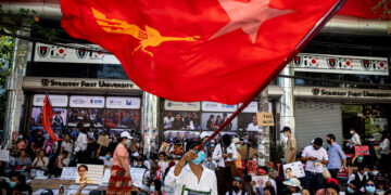 An NLD supporter waves the party’s flag during an anti-regime protest in Yangon on Feb. 13. / The Irrawaddy