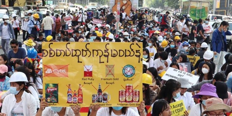 Anti-coup protesters hold a placard reading ‘Don’t buy goods produced by the military’ to show their stand against the military regime in Yangon in February. / Don’t Buy it / Facebook