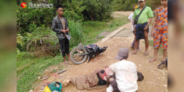 The father (sitting) and his slain son (lying) at the scene after the shooting on May 23. / The Irrawaddy