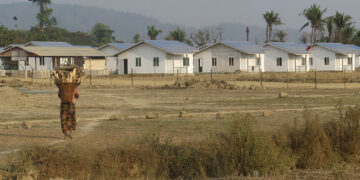 An ethnic Arakanese woman walks by a newly built ‘model village’ in northern Rakhine’s Maungdaw Township early this year.  / Moe Myint / The Irrawaddy