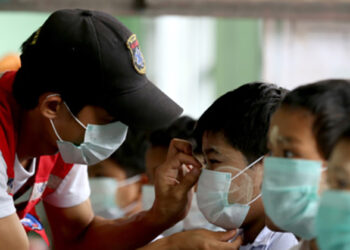 A volunteer distributes masks at a school. / The Irrawaddy