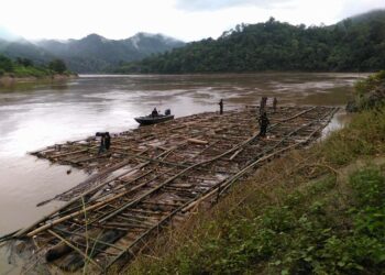 Thai border guard soldiers and Karen National Liberation Army soldiers examine logs seized in KNLA Brigade 5 territory on the Salween River in Sept. 2016. / Mutraw Mobile Team