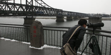 A Chinese visitor uses a pair of binoculars to look from the Chinese city of Dandong to Sinuiju in North Korea. / Reuters