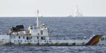 A Vietnamese naval vessel, with a Chinese oil drilling rig visible in the background, patrols in the South China Sea near the Paracel Islands in 2014. The islands are claimed by China and Vietnam. / Kyodo