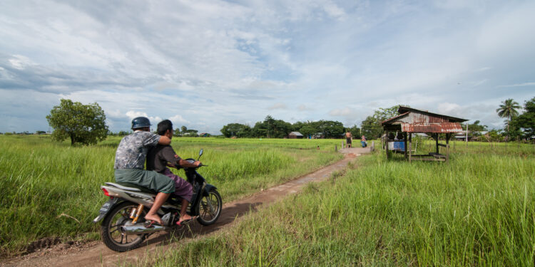 Two men ride on a motorcycle in the outskirts of Rangoon. / The Irrawaddy