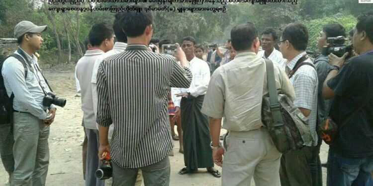 U Shuna Myar (center, in long-sleeved white shirt and green longyi) speaks with 13 journalists in Ngakhura village of northern Maungdaw, Arakan State. The Burmese text at the top of the photo states, “Shuna Myar (in the white shirt) talks to the media.” / Myanmar President Office / Facebook