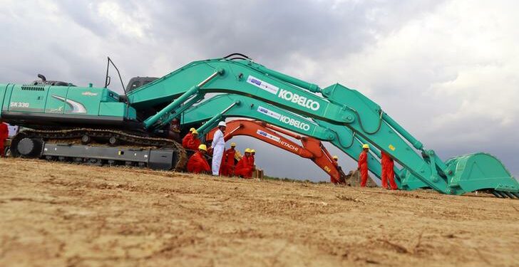 Workers stand next to excavators during the commencement ceremony of the Thilawa Special Economic Zone (SEZ) project in the Japanese Special Economic Zone at Thilawa outside Rangoon on November 30, 2013. / Soe Zeya Tun / Reuters