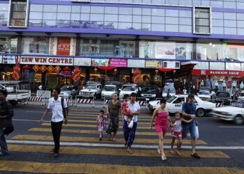 People cross a road after shopping at the newly opened Tawwin shopping center in Yangon in 2012. / REUTERS