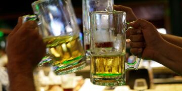 People toast with beer at a bar. / Reuters