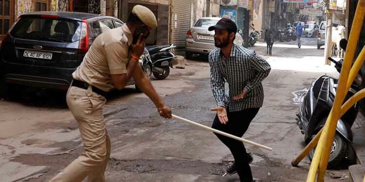 A police officer wields his baton against a man as punishment for breaking the lockdown rules after India ordered a 21-day nationwide lockdown to limit the spreading of coronavirus disease, in New Delhi, India on March 25, 2020. / REUTERS