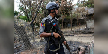 A police officer stands guard near a house that was burnt down in Maungdaw, northern Rakhine State, on Aug. 30, 2017. / REUTERS