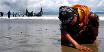 A Rohingya refugee touches the shore at Shah Porir Dwip after crossing the Bangladesh border by boat through the Bay of Bengal in September 2017. / Reuters