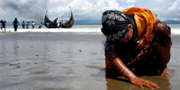 A Rohingya refugee touches the shore after crossing the Bangladesh border at Shah Porir Dwip in September 2017. / REUTERS