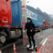 A Vietnamese health worker looks on as a Chinese trader wearing a protective mask rides a hoverboard along container trucks going from China to Vietnam, at the Huu Nghi border gate with China, in Lang Son province, Vietnam, on Feb. 20, 2020. / REUTERS