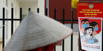 A farmer rides a bicycle past a poster warning about COVID-19 in Hanoi, Vietnam on April 22, 2020. / REUTERS