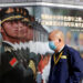 A man wearing a mask walks past a military poster on Financial Street in central Beijing on Feb. 3, 2020. / REUTERS
