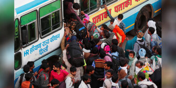 Migrant workers try to board a crowded bus as they return to their villages during a 21-day nationwide lockdown to limit the spread of COVID-19, in Ghaziabad, on the outskirts of New Delhi, India, on March 29, 2020. / REUTERS