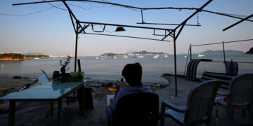 A resident of Hong Kong’s Nim Shue Wan village on Lantau Island faces Peng Chau Island and its surroundings, the proposed site of the government’s East Lantau Metropolis project, in October 2019. / Reuters