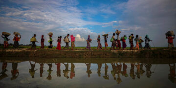 Rohingya refugees are reflected in rainwater in paddy fields after fleeing Myanmar into Palang Khali, near Cox's Bazar, Bangladesh on Nov. 2, 2017. / Reuters