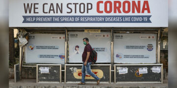 A man wearing a protective mask walks past a bus stop displaying preventive measures against the coronavirus in Mumbai, India, on March 18, 2020. / REUTERS