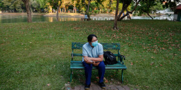 A person wears a protective face mask while sitting on a bench in Bangkok’s Lumphini Park on April 1, 2020. Authorities announced that all parks in the Thai capital will be closed amid the spread of COVID-19. / Reuters
