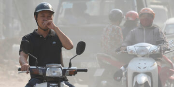 A man covers his nose and mouth as he drives through polluted air in Hanoi on Oct. 1, 2019. / REUTERS