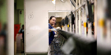 A migrant worker from Myanmar tests the quality of a monitor on a TV assembly line at a factory in Bangkok on July 22, 2019. / REUTERS