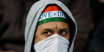 A spectator covers his mouth with a scarf as he waits for the start of a cricket match at Himachal Pradesh Cricket Association Stadium in Dharamsala, India on March 12, 2020. / REUTERS