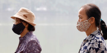 Vietnamese women wear protective masks while walking around Hoan Kiem Lake in Hanoi, Vietnam on Oct. 2, 2019. / Reuters