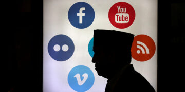 A man walks in front of social media logos at the Jakarta Convention Center in Jakarta, Indonesia. / Reuters