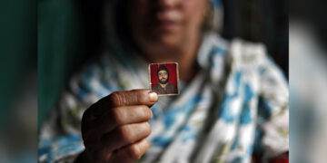 Haseena Malik shows a photograph of her son Uzair Maqbool Malik at her house in Shopian, Kashmir, in September 2019. Malik, who participated in anti-government protests in 2016 but has not been convicted of a crime, is detained in a jail 1,000 km away in Agra, Uttar Pradesh state. / REUTERS