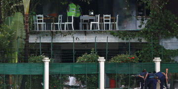 Policemen sneak a look inside the Holey Artisan Bakery and the O'Kitchen Restaurant as others inspect the site after gunmen attacked, in Dhaka, Bangladesh, July 3, 2016. / Reuters / Adnan Abidi TPX IMAGES OF THE DAY