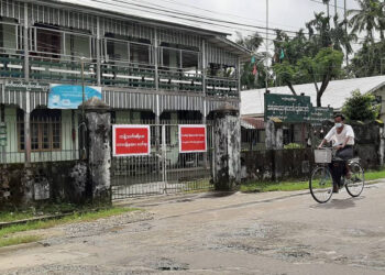 A local resident is seen on a deserted road in Sittwe after the government imposed a partial lockdown to curb the spread of COVID-19. / Min Aung Khine / The Irrawaddy