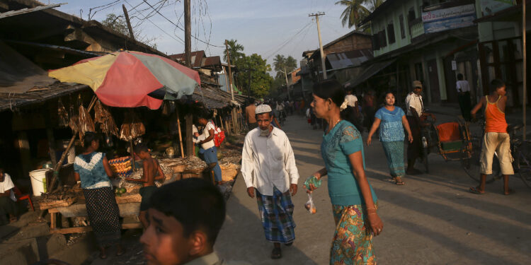 People walk between stalls at a market in Maungdaw town in northern Arakan State on November 11, 2014. / Reuters