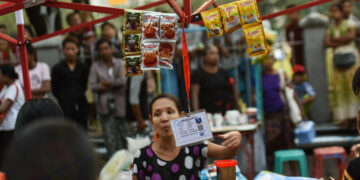A street vendor is seen at the Strand Road night market with her registration card provided by the YCDC. / Pyay Kyaw / The Irrawaddy