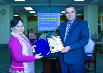 Central Bank Deputy Governor Daw Khin Saw Oo presents a certificate for mobile financial services to Wave Money CEO Brad Jones. / Wave Money