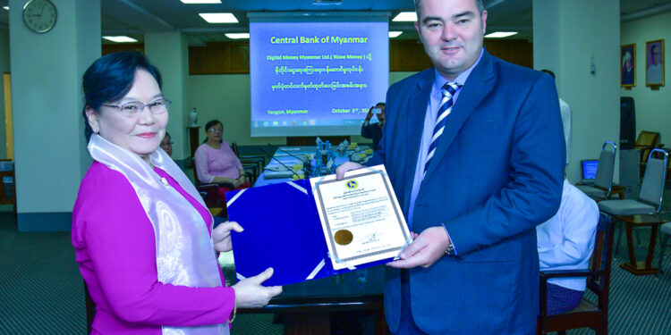 Central Bank Deputy Governor Daw Khin Saw Oo presents a certificate for mobile financial services to Wave Money CEO Brad Jones. / Wave Money