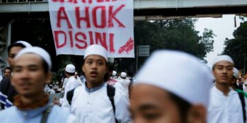 Members of Muslim groups walk in front of a banner referring to Jakarta Governor Basuki Tjahaja Purnama by his nickname during a protest against the governor in Jakarta, Indonesia. The banner reads, “Hang Ahok here.” / Beawiharta / Reuters