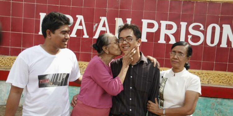 Burmese blogger Nay Phone Latt's grandmother (2nd L) kisses him as he reunites with his mother (R) and elder brother (L) in front of Pa-an prison, in Pa-an January 13, 2012. / Soe Zeya Tun / Reuters