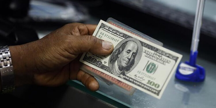 A man holds a $100 bill at a currency exchange counter in Yangon in July 2016. / The Irrawaddy