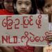 A girl holds a sign as Daw Aung San Suu Kyi campaigns in her constituency of Kawhmu Township, outside Yangon, September 21, 2015. The sign reads: Vote for NLD for an amended constitution. / Reuters