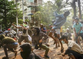 Anti-coup protesters aim slingshots at approaching security forces in Yangon on March 28, 2021. / Getty / Kyodo