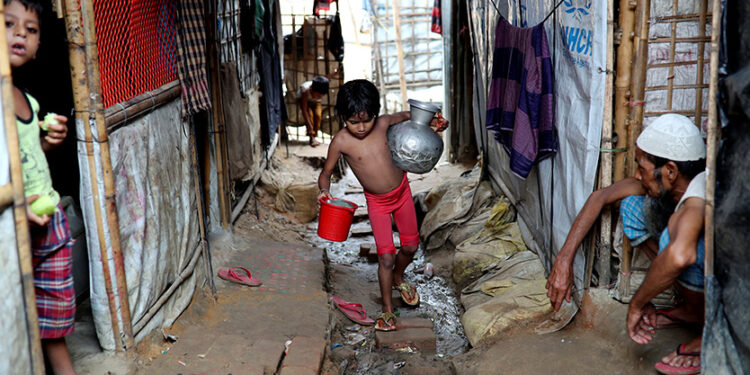 A Rohingya refugee girl carries water jars in the Kutupalong camp in Cox's Bazar, Bangladesh August 24, 2018. / REUTERS