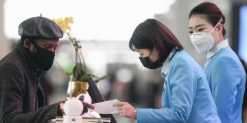 Airport employees and a passenger are seen wearing masks in a departure lobby at Beijing international airport on Jan. 27, 2020, amid the outbreak of a new pneumonia-causing coronavirus that has spread overseas. / Kyodo