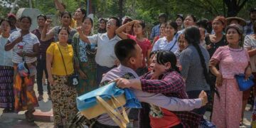 A newly released prisoner embraced his sister outside Obo Prison in Mandalay while others waited for more releases after the president's amnesty on Tuesday. / Zaw Zaw / The Irrawaddy