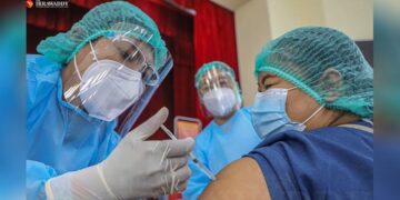 A health-care worker in Mandalay receives their first COVID-19 vaccine jab as part of a nationwide program launched on Wednesday. / Zaw Zaw / The Irrawaddy